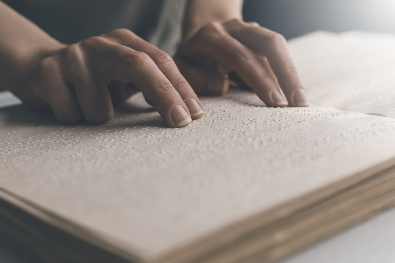 fingers touching a book with Braille on the pages
